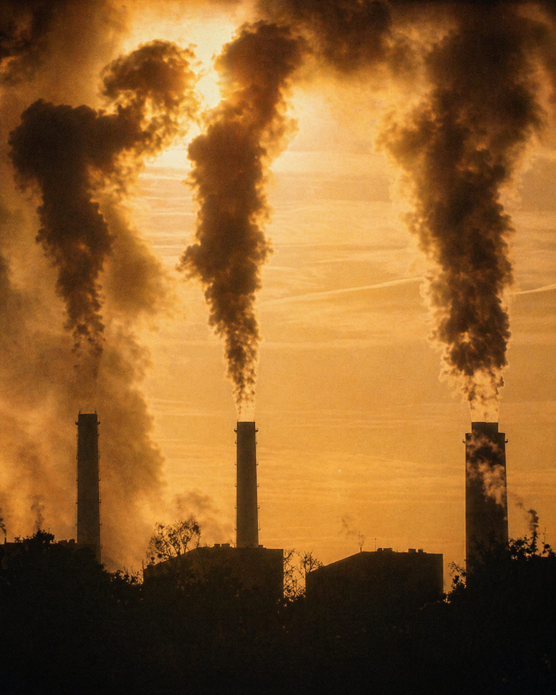 Smokestacks releasing emissions at sunset